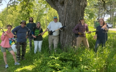 A group of volunteers with a shovel-looking tool called a Parsnip Predator after a weed workday. 