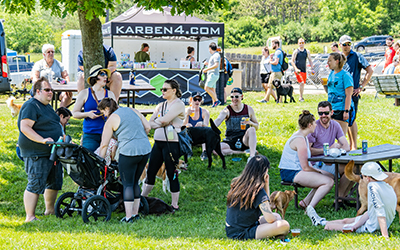 Karben 4 tent in the background. Lots of happy people at picnic tables with dogs.