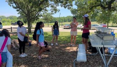 kids standing in the shade watching a presentation about rainfall