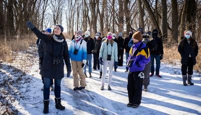 A group of people on a snowy trail looking for birds.