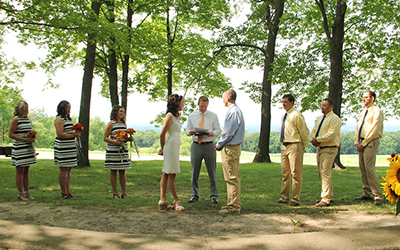 Couple and wedding party standing under the trees