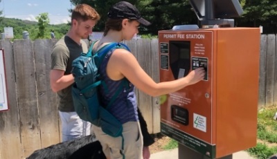 Parks visitors purchase a permit at an electronic pay station.