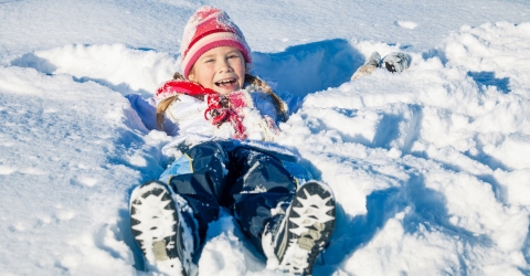 child in snow making snow angels